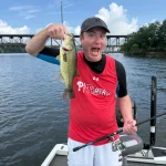 Jesse making a funny face while holding a largemouth bass on a fishing boat in Chesapeake Bay.