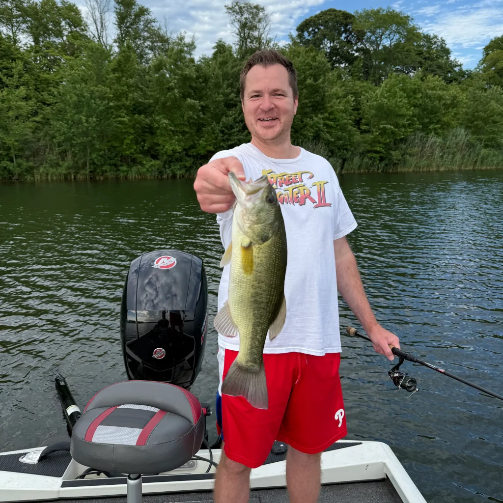 Jesse holds large bass caught at DOD Lake in New Jersey from boat with fishing equipment visible.