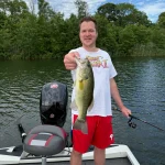 Jesse holds large bass caught at DOD Lake in New Jersey from boat with fishing equipment visible.