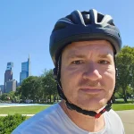 Jesse wearing blue bicycle helmet on Philadelphia Parkway with museums district skyline behind