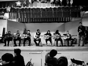 Black and white photo of music students from Our Lady of Mt Carmel performing with guitars on stage during a concert.