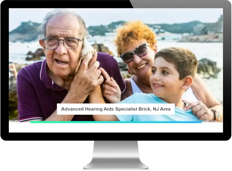 Desktop monitor displaying Fischer Hearing hero banner with family at beach and text 'Advanced Hearing Aids Specialist Brick, NJ Area'